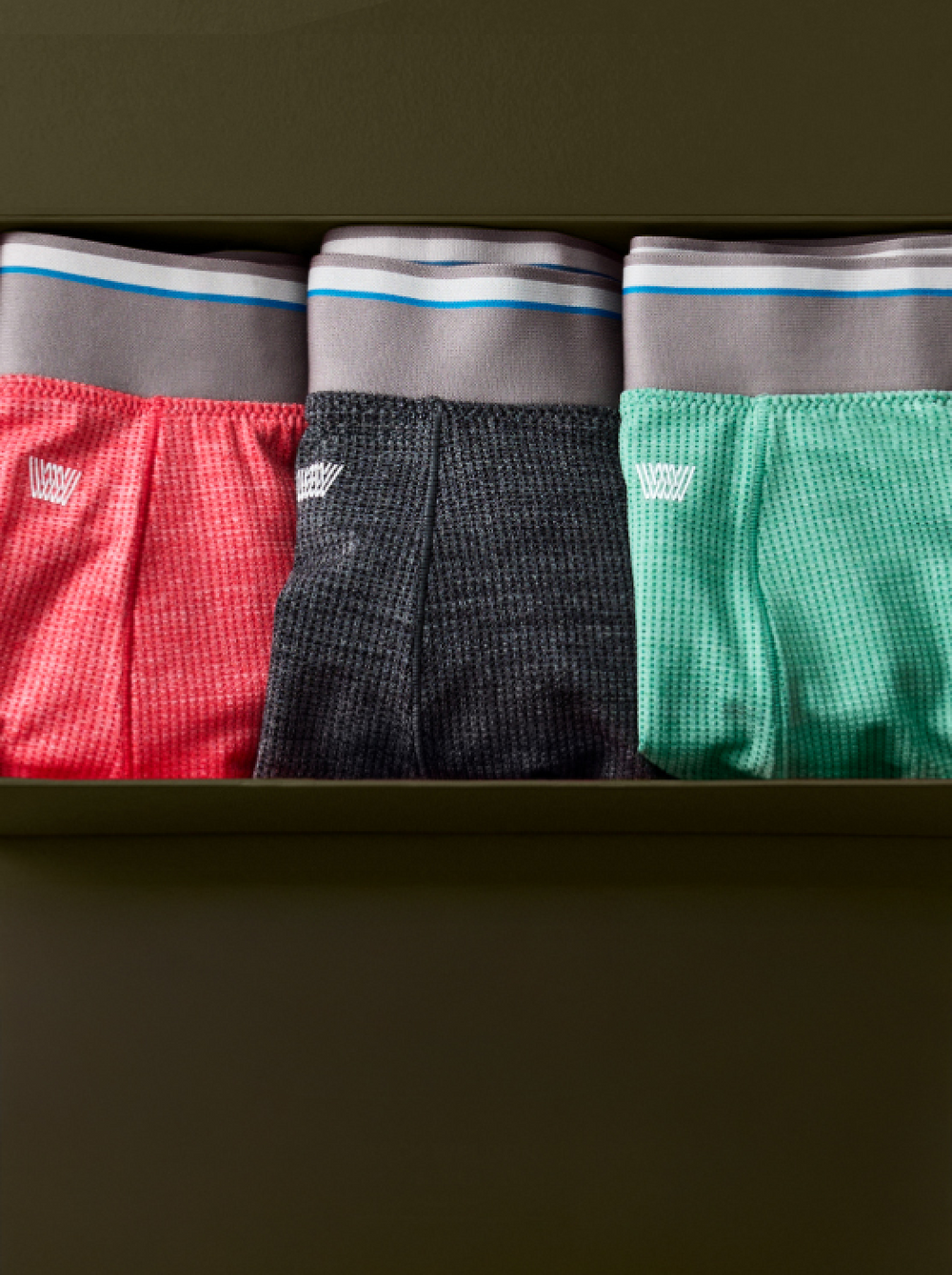 Three folded boxer briefs laid side-by-side in a drawer.