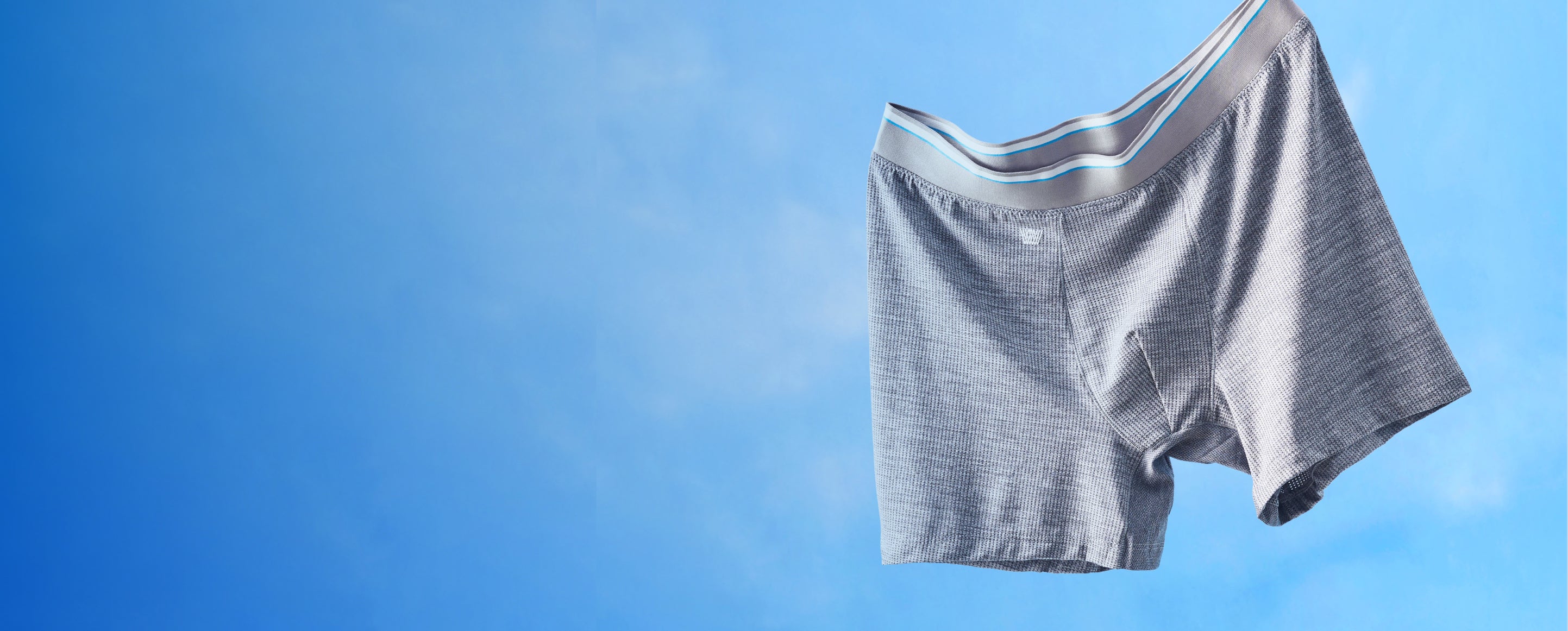 image of a grey pair of AIRKNITx boxer brief floating in the air with a blue sky background