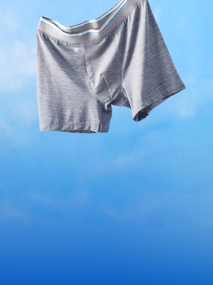 image of a grey pair of AIRKNITx boxer brief floating in the air with a blue sky background