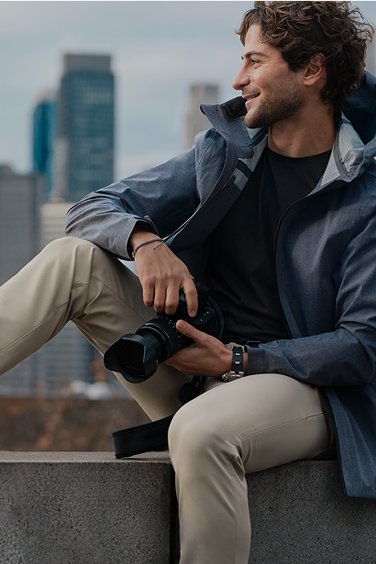 man sits on a ledge with his camera