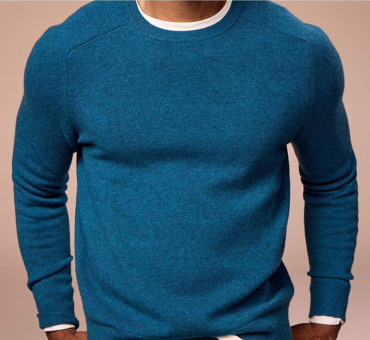 Blue sweater worn by a person on a beige background