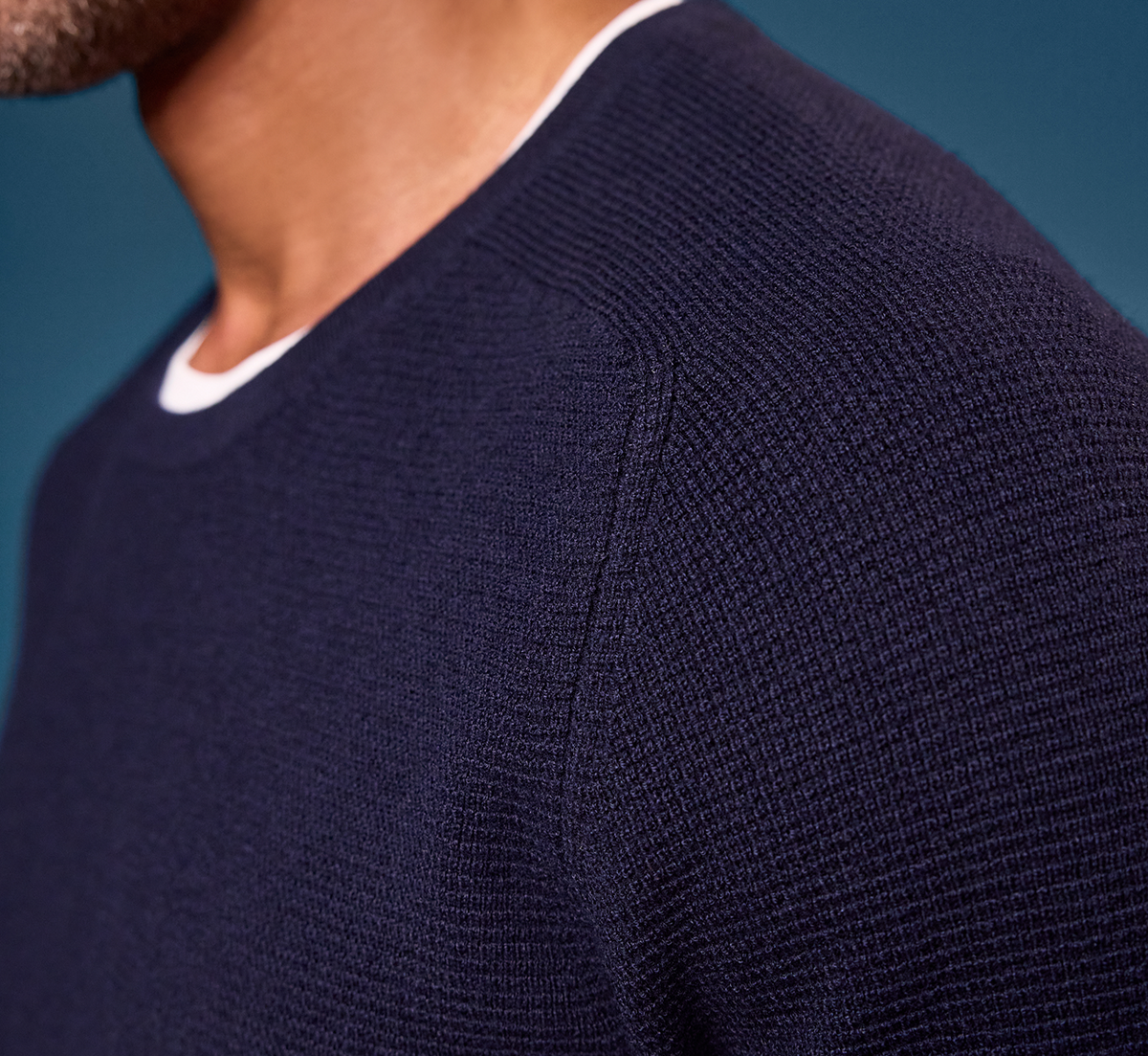 Navy blue textured sweater on a person against a blue background