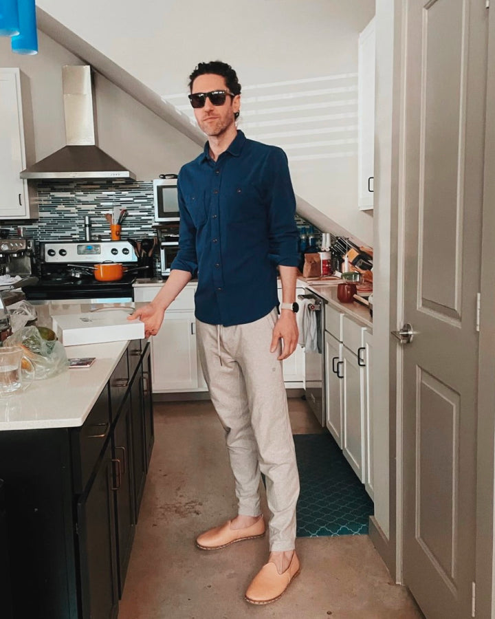 Man in his kitchen wearing a navy blue button up and cream sweatpants