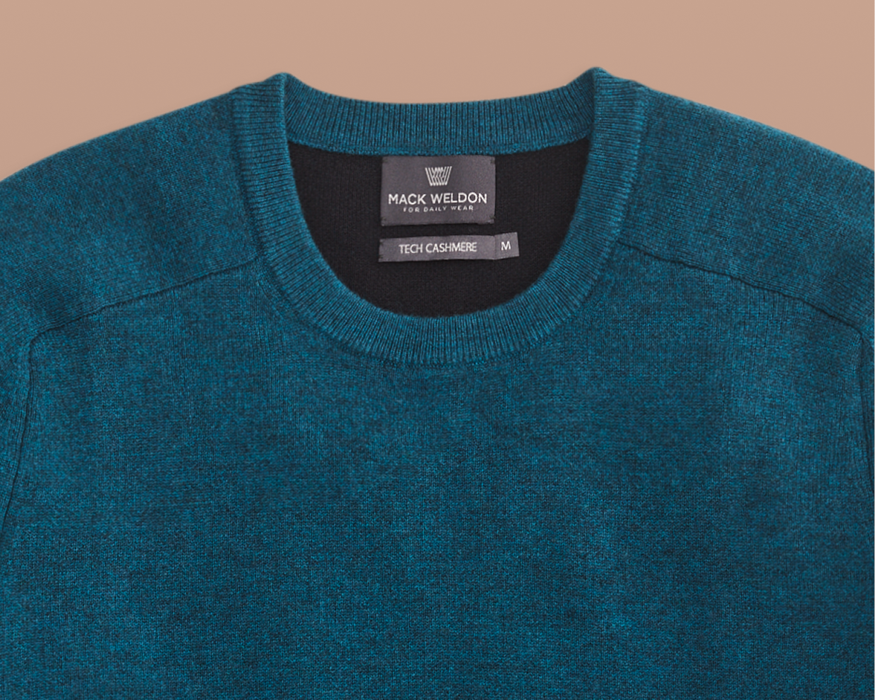 Teal sweater with Mack Weldon label on a beige background