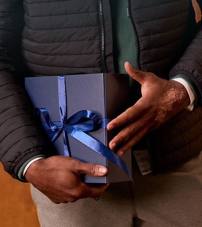 Person holding a wrapped gift with a blue ribbon