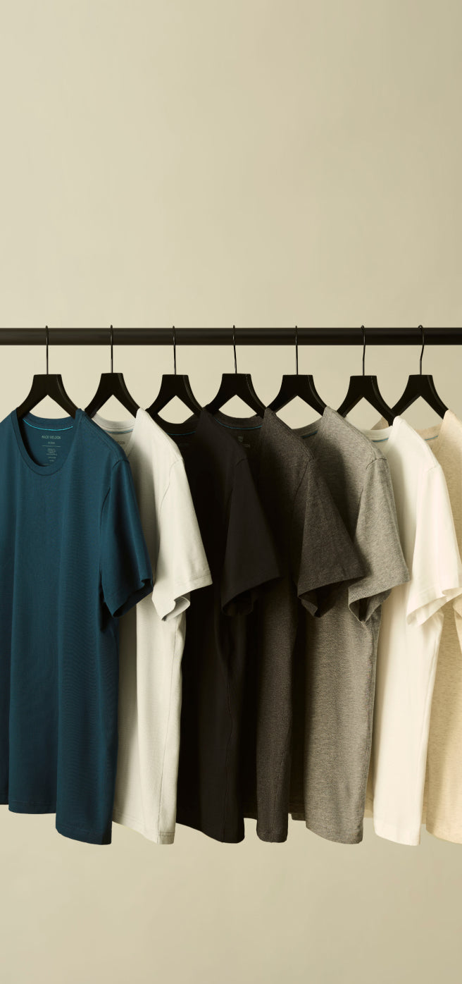 A row of Mack Weldon T-shirts hanging on black hangers 