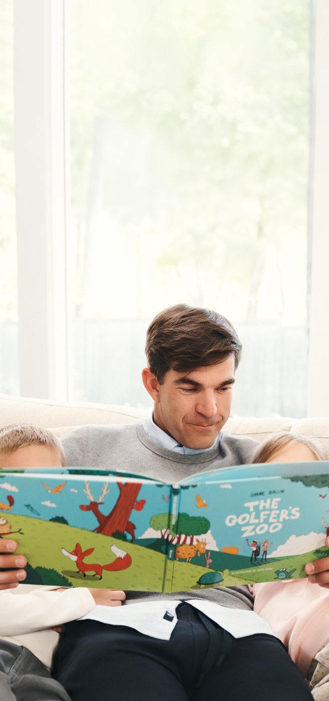 Man with his children reading the Golfer's Zoo book