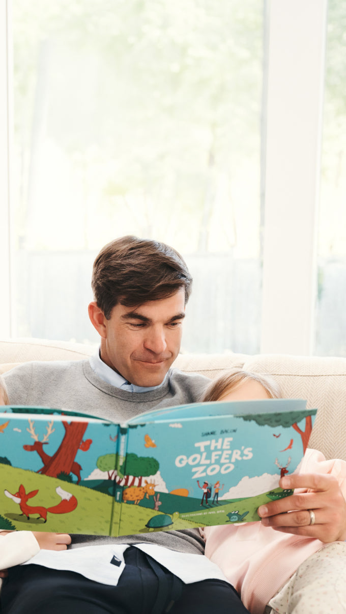 Man with his daughter reading The Golfer's Zoo Book 