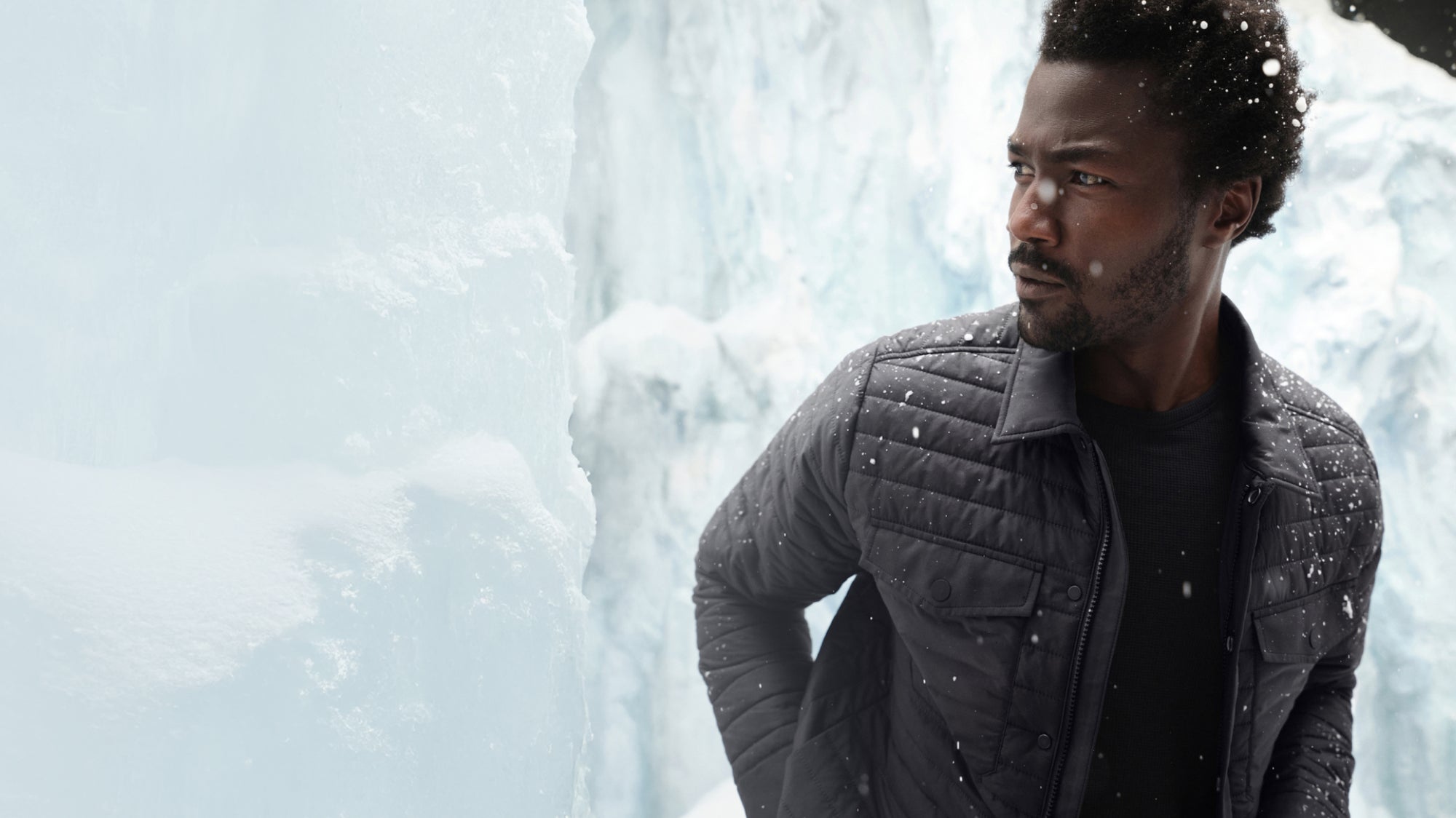 Man wearing a WARMKNIT puffer jacket walking with an ice like background