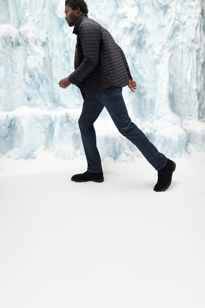 Man wearing a WARMKNIT puffer jacket walking with an ice like background