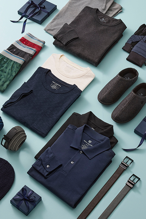 Collection of folded clothing and accessories on a light blue background