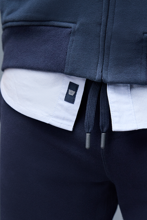 Close-up of a navy blue jacket with a brand logo on a white background