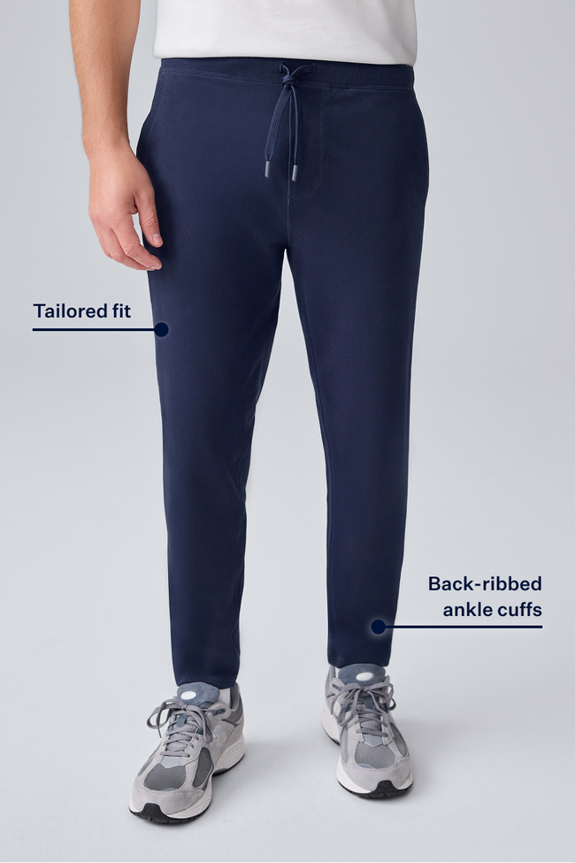 Navy blue jogger pants with text highlighting features on a light gray background