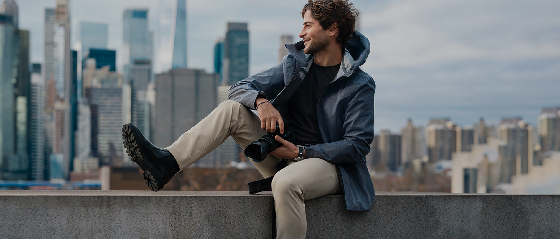 man sits on a ledge with his camera
