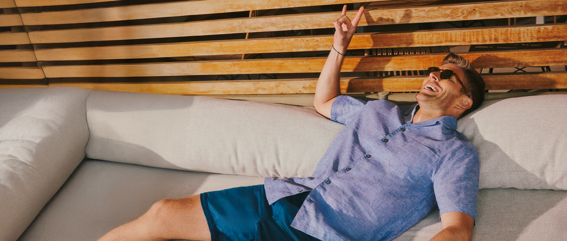 Man lying on a couch with a wooden wall in the background