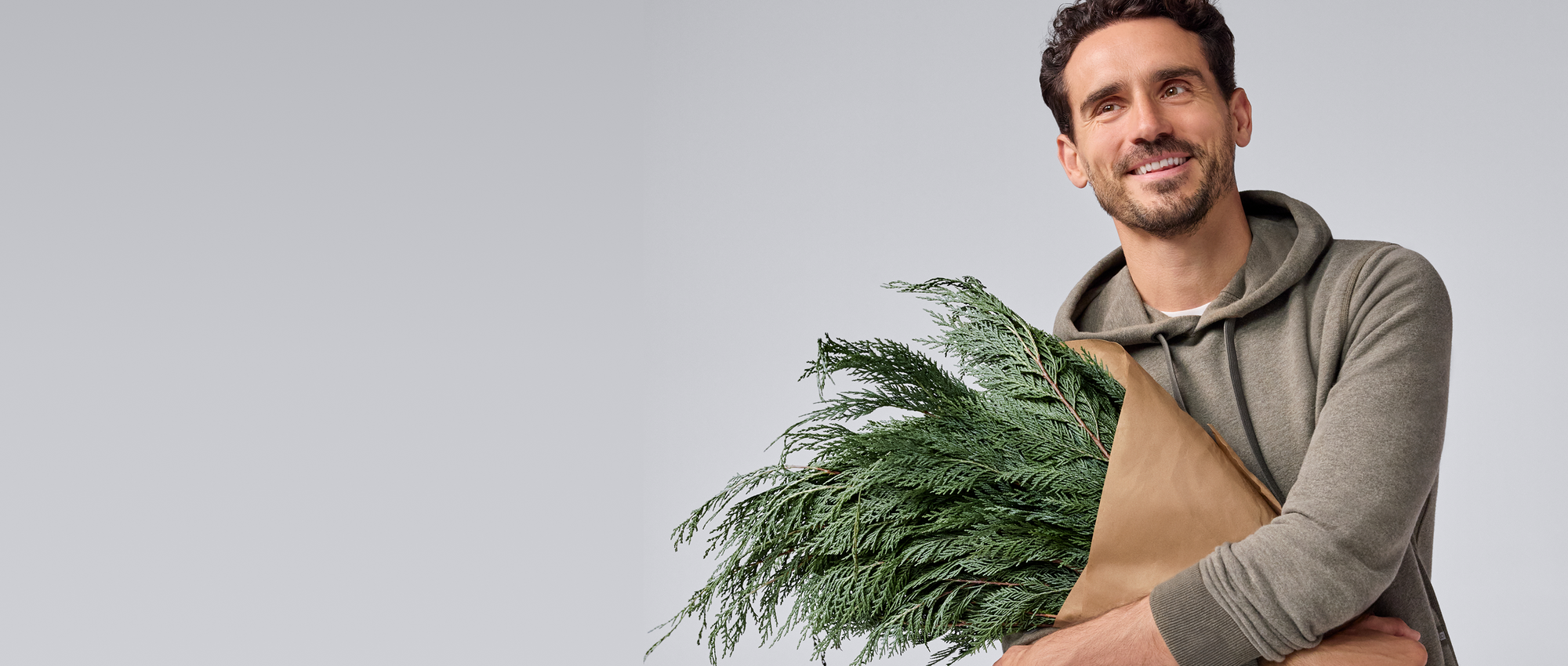 Man holding a bundle of greenery against a plain background