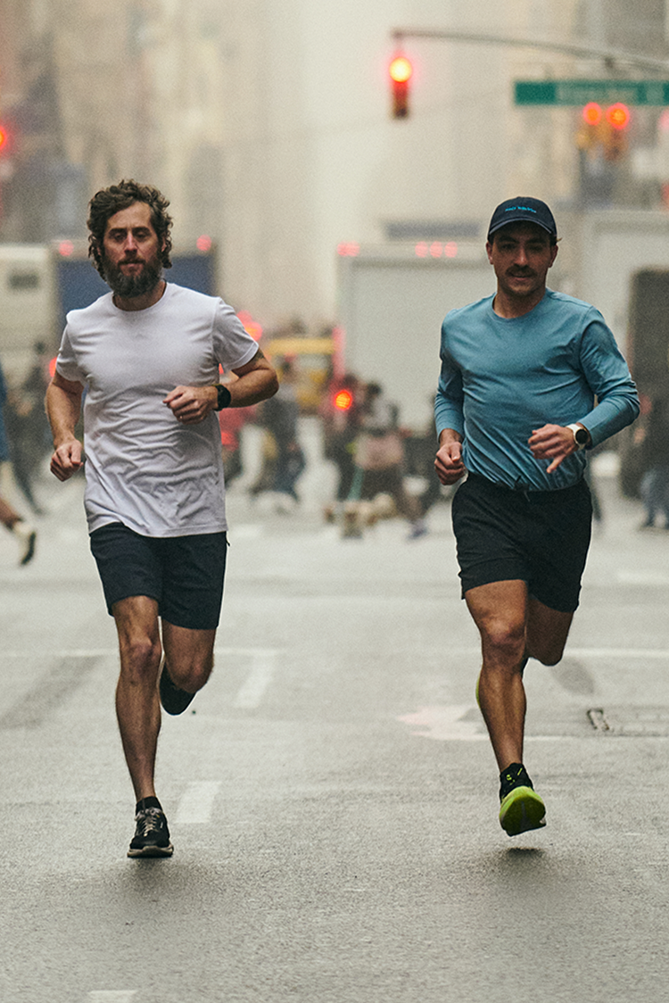 Two men run in the middle of wide busy street