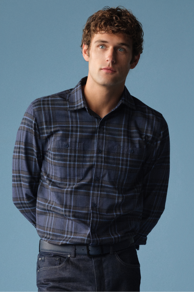 man wears navy blue button up long sleeve polo with a blue backdrop