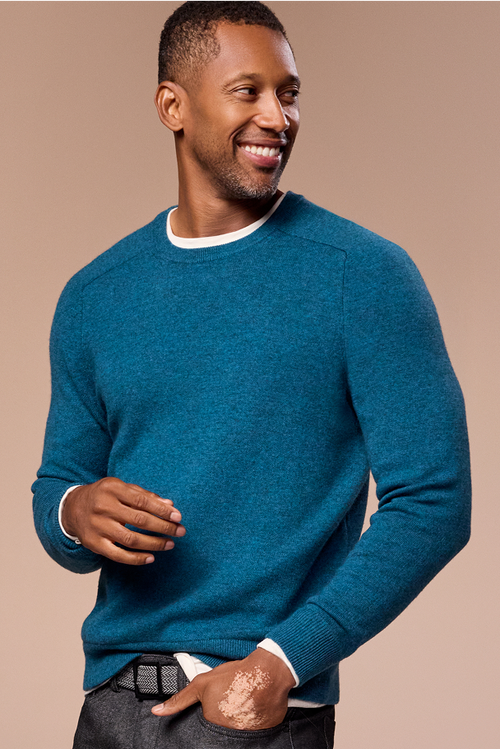 Man wearing a blue sweater against a beige background