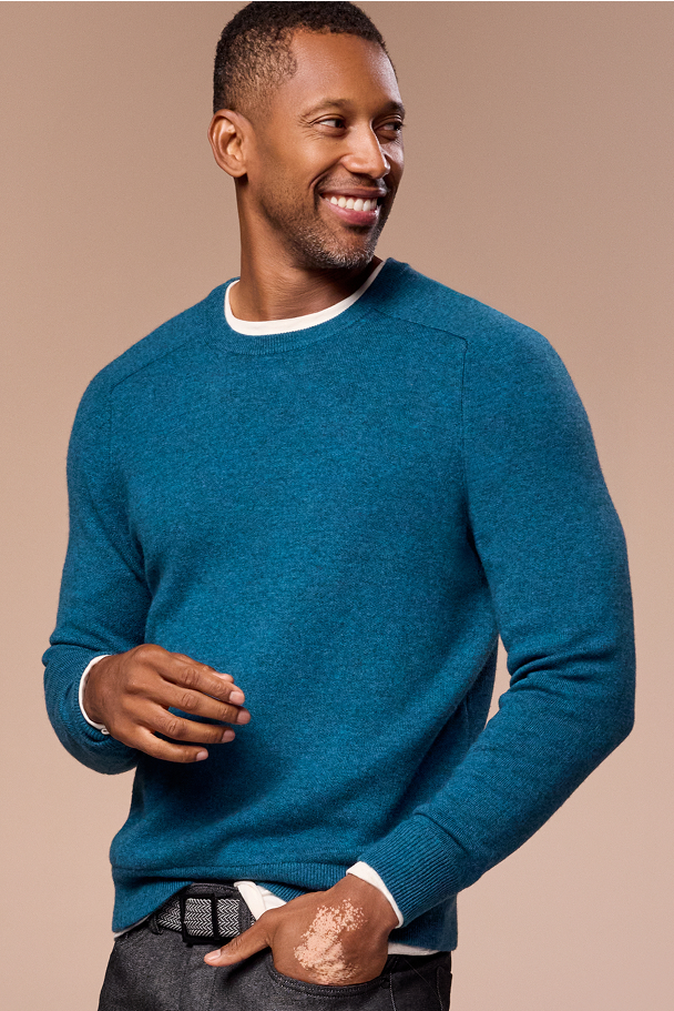 Man wearing a blue sweater against a beige background
