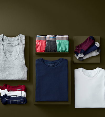 Collection of men's clothing including shirts, pants, and socks on a brown background