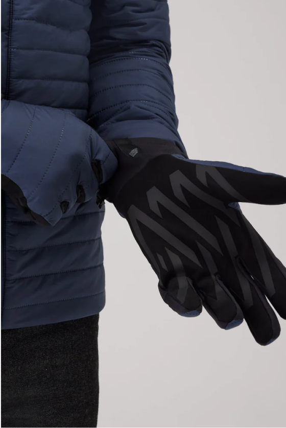 Person wearing a double sided dark blue quilted jacket adjusts a patterned dark winter glove.