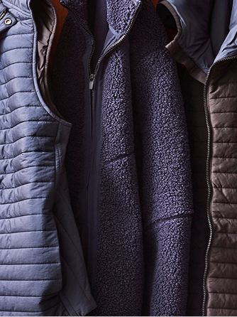 Close-up of a layered jacket with a quilted blue jacket over a dark fleece vest.